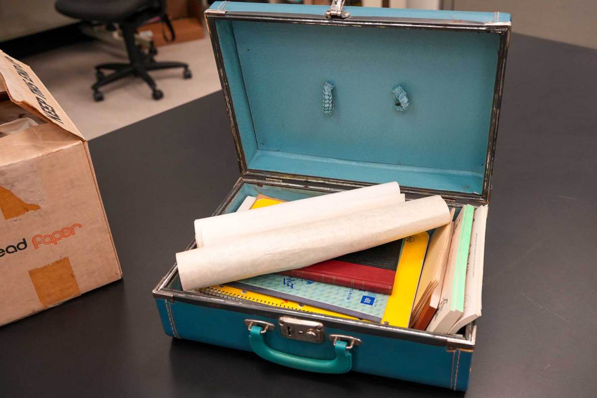 A blue briefcase opened on a table, filled with papers and booklets