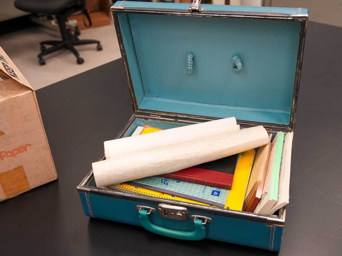 A blue briefcase opened on a table, filled with papers and booklets