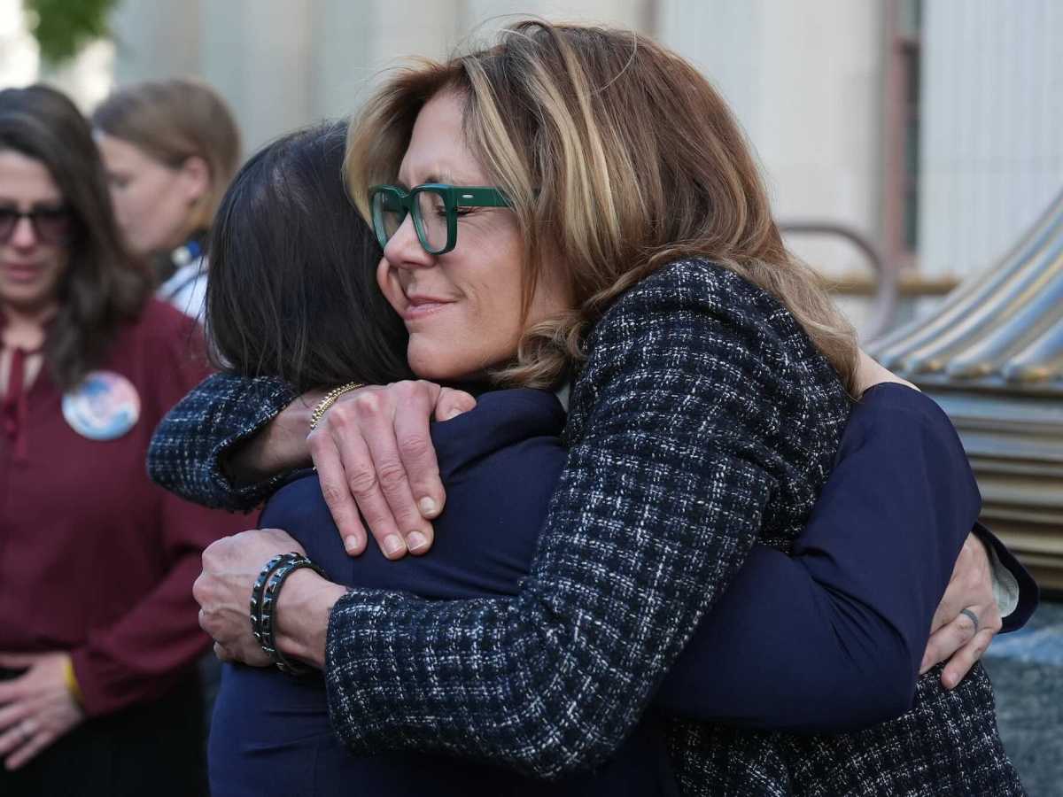 Two women hugging outside of a courthouse