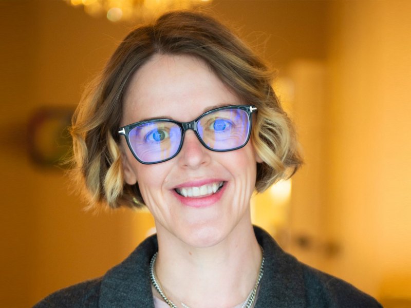 Headshot of Lauren Stokes, in glasses, in a warm toned room