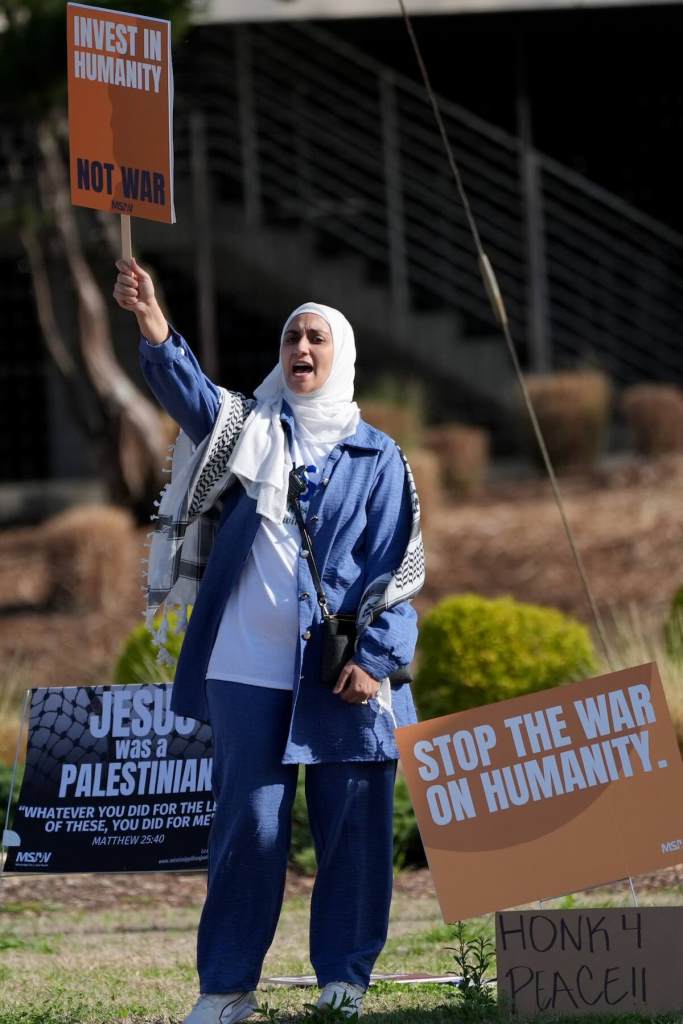 A closeup of a woman holding a sign that reads 'Invest in Humanity'
