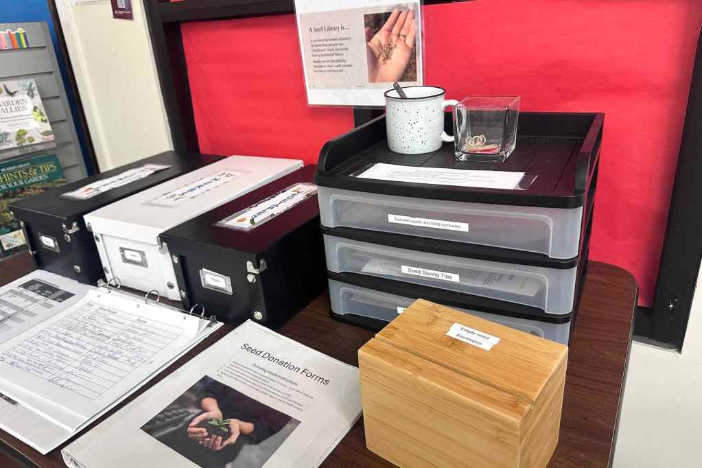 Boxes of seeds and a signin page sit on a desk