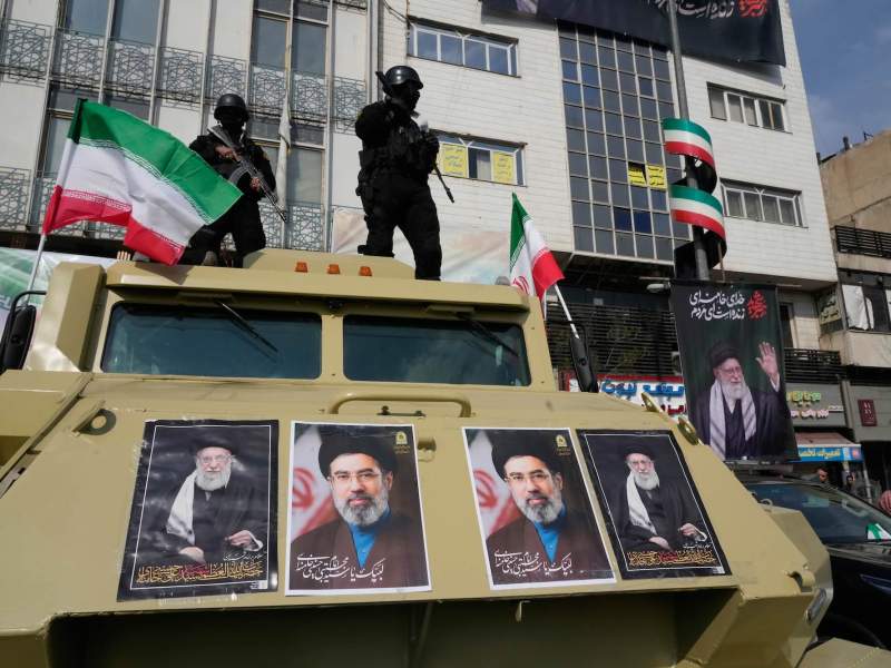 Police stand on top of their tank displaying photos of Ayatollah Ali Khamenei and his son Ayatollah Mojtaba Khamenei