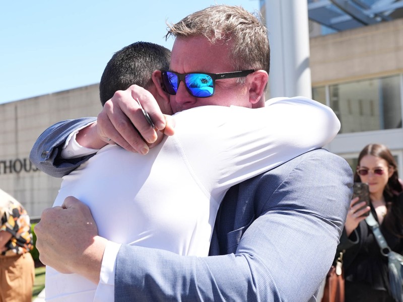 Brothers Ted DiBiase Jr. and Brett DiBiase hug outside a courthouse