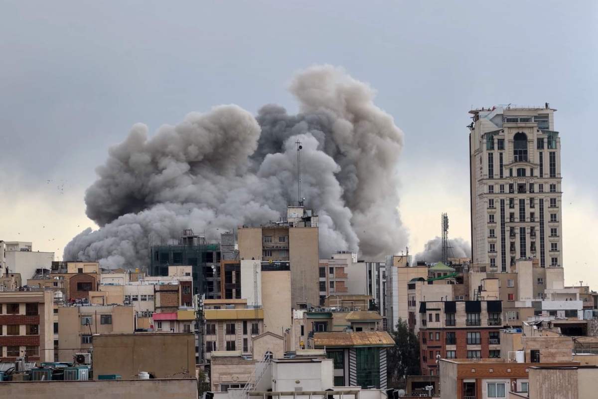 A large plume of smoke from a bombing rises from a cityscape