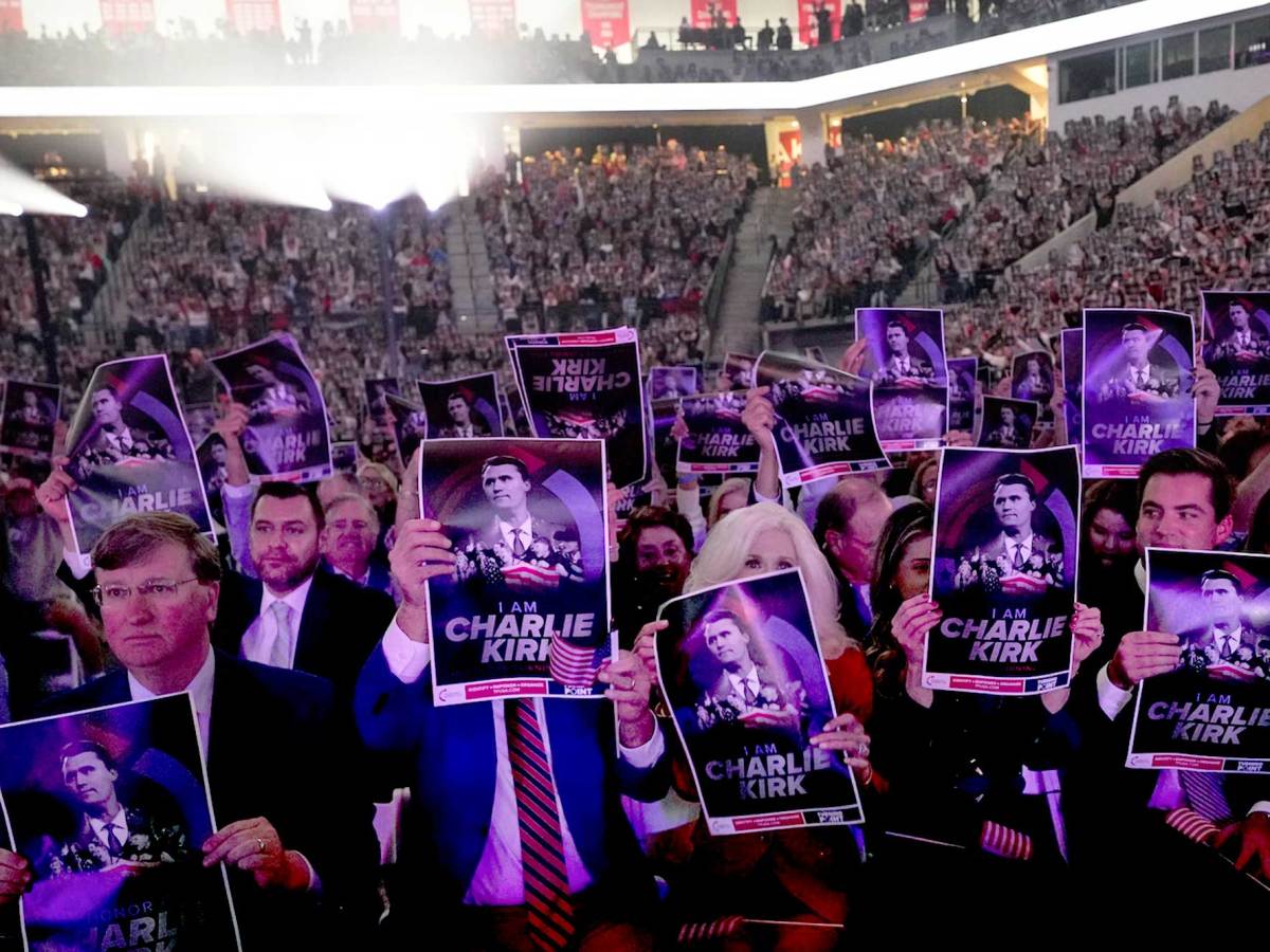 A large venue full of people including Tate Reeves holding up signs that say 'I am Charlie Kirk'