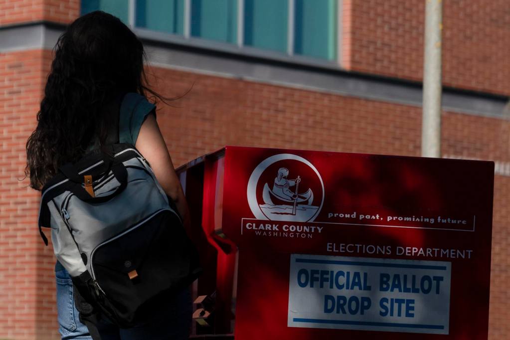 A woman walks up to a red box labeled Clark County Official Ballot Drop Site
