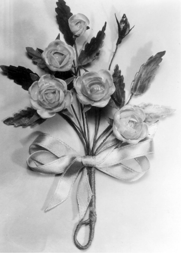 A black-and-white photo of flowers and leaves arranged as a corsage