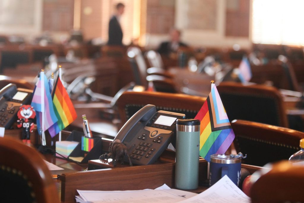 A series of desks with small decorative pride and trans flags on display.