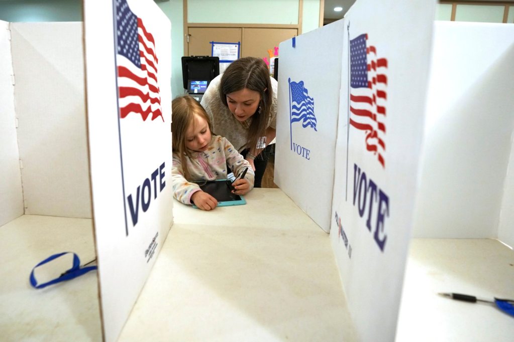 A mother casts her vote with the held of her young daughter