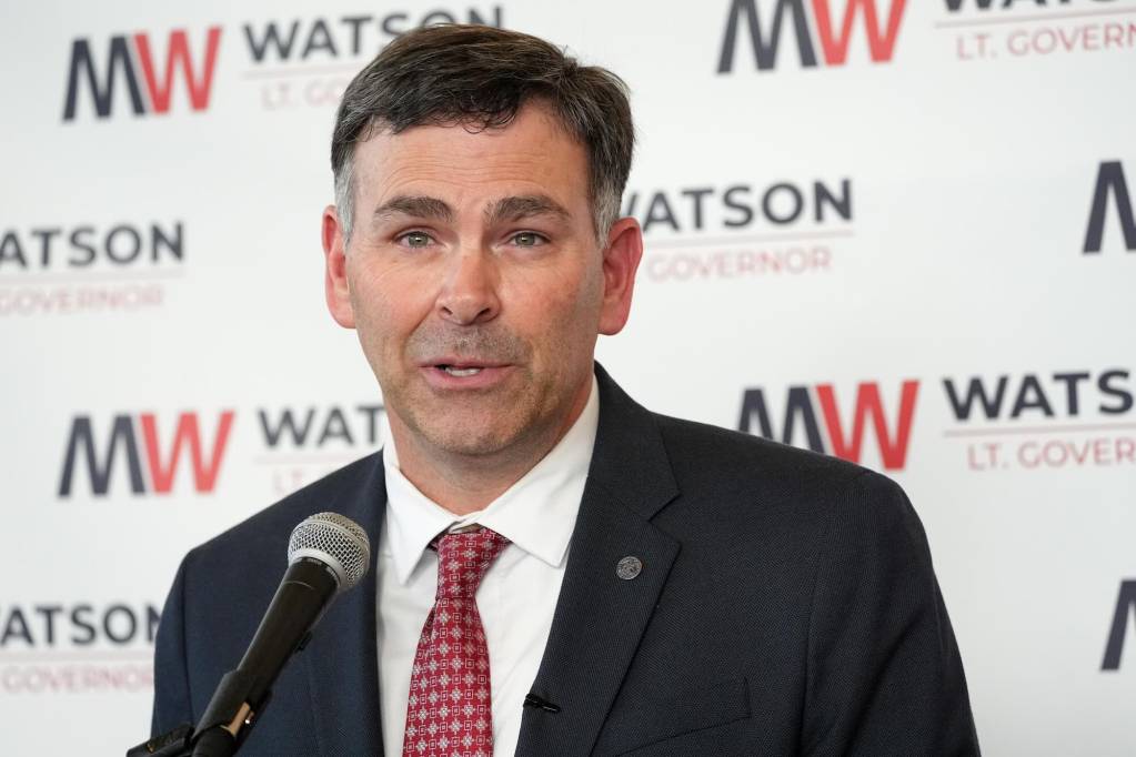 Michael Watson speaks at a press conference in front of a wall covered with MW logos that read Watson Lt. Governor