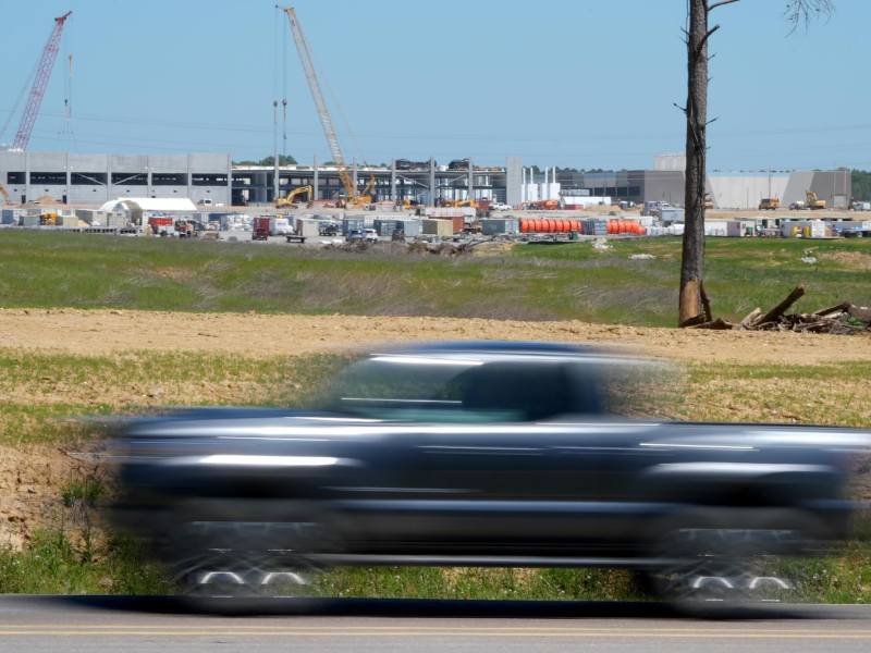 A distant construction site seen past a road with blurry cars