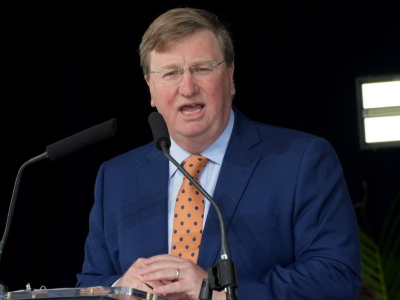Tate Reeves, in a blue suit and gold tie, speaks at an Amazon press conference