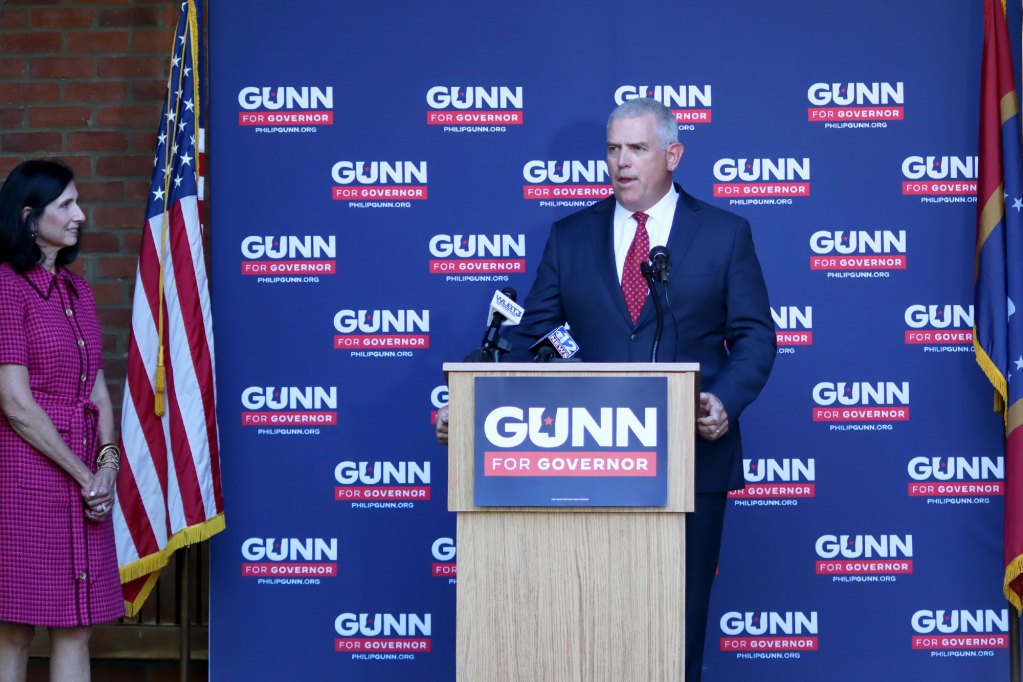 Philip Gunn speaks at a podium in front of a wall covered in repeating logos that reads Gunn for Governor