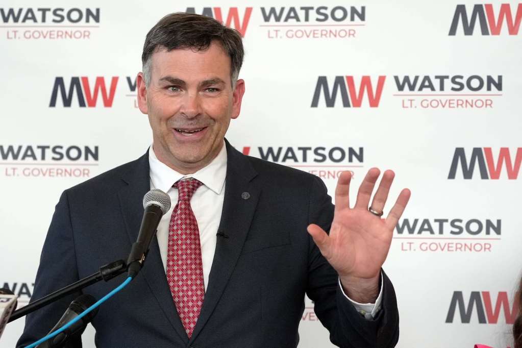 Michael Watson speaks at a press conference in front of a wall covered with MW logos that read Watson Lt. Governor
