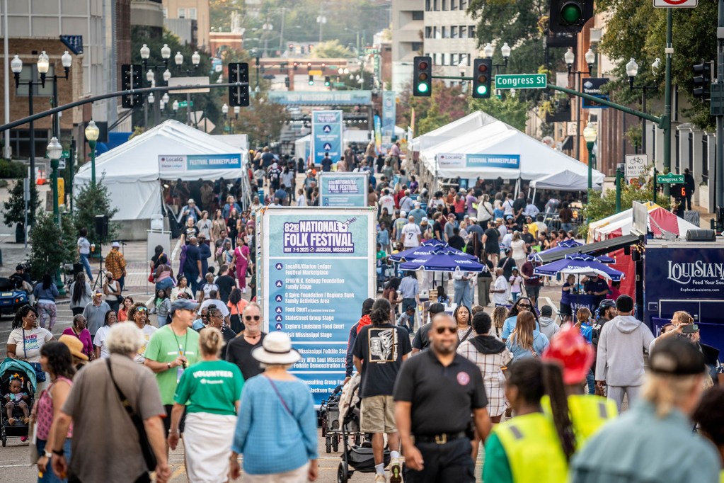 A downtown street is filled with event tents and people attending