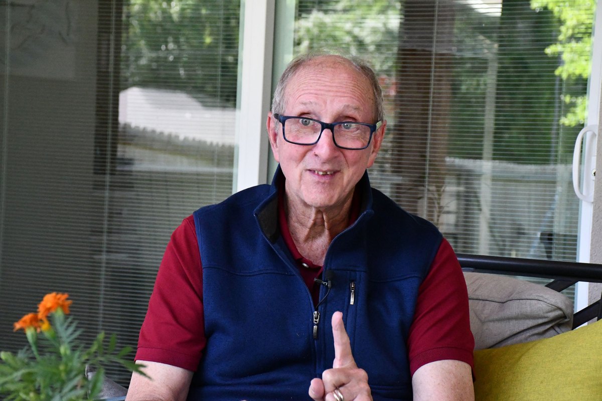 Jan Vest gestures while seated on an outside porch