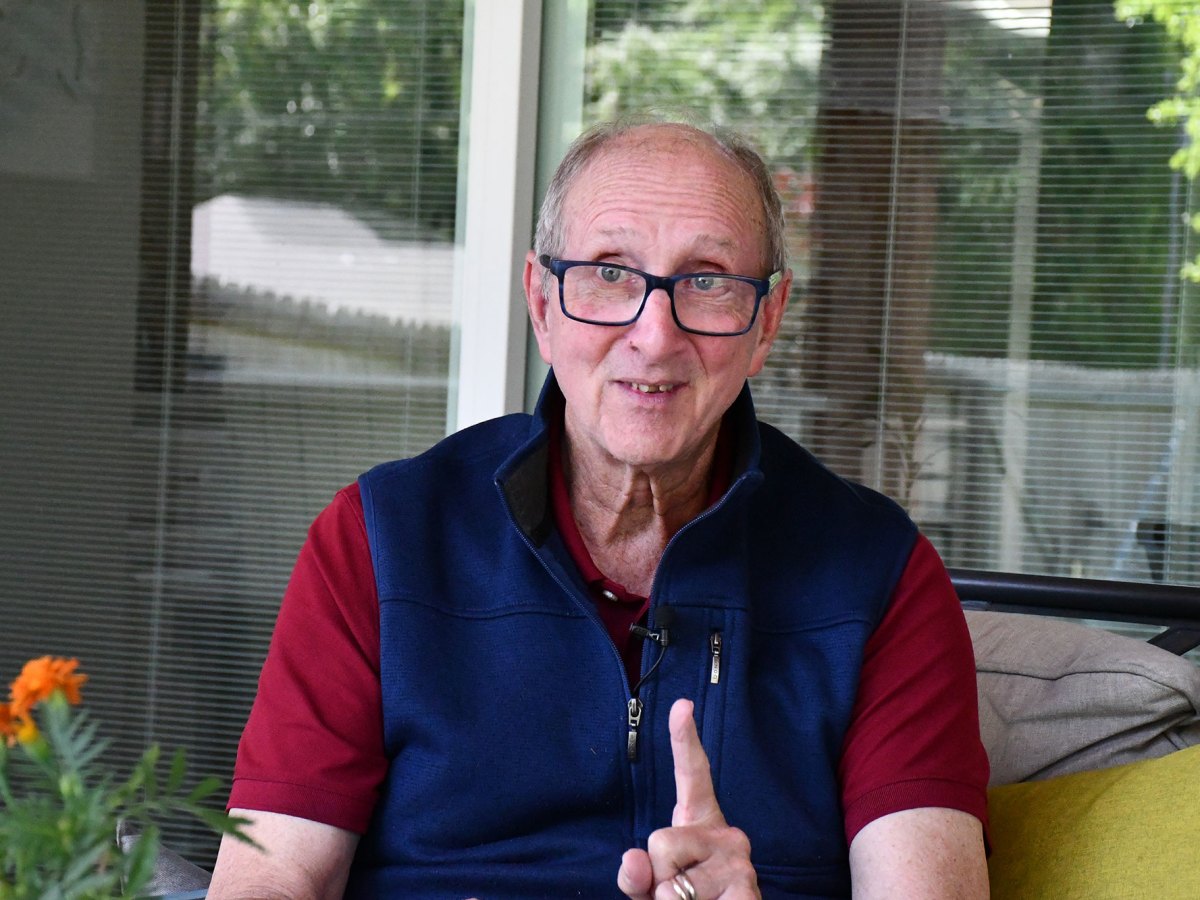 Jan Vest gestures while seated on an outside porch