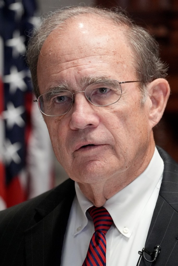 Delbert Hosemann wearing a black suit in front of an American flag.