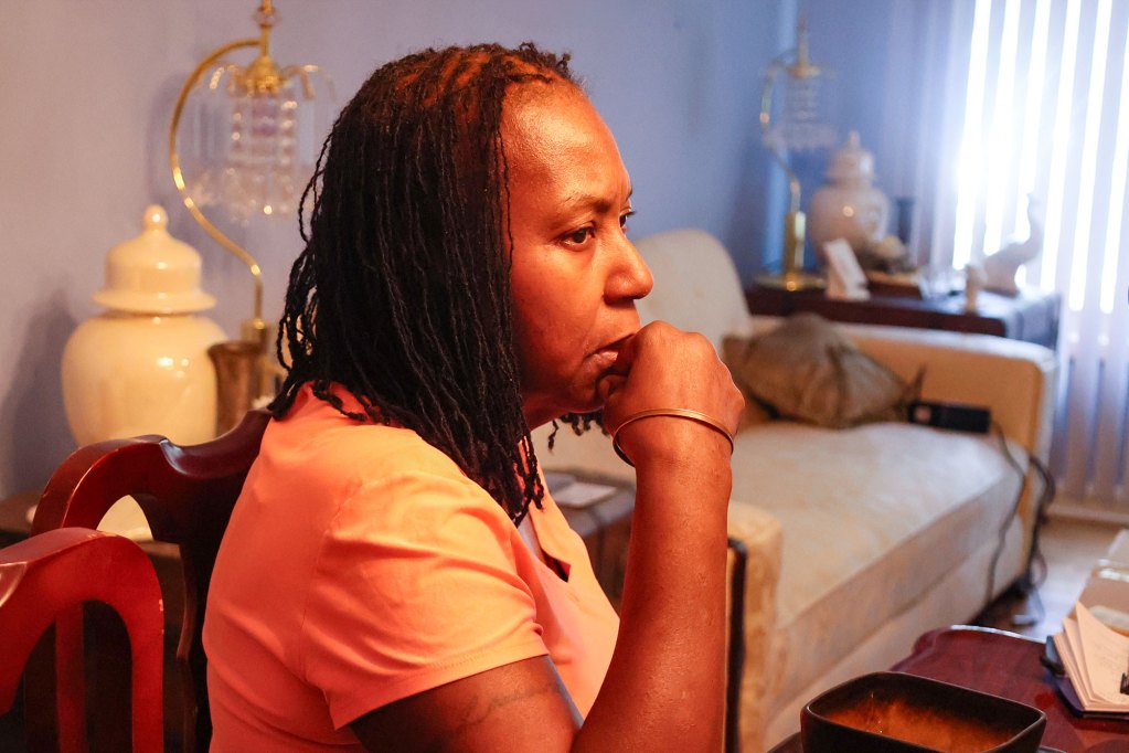 A woman seated at her dining room table, hand against chin as she listens to others talk