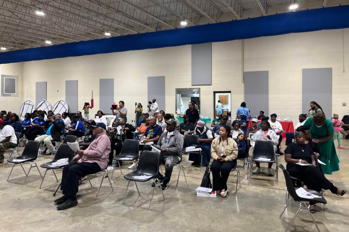 Numerous people seated in chairs inside a building.