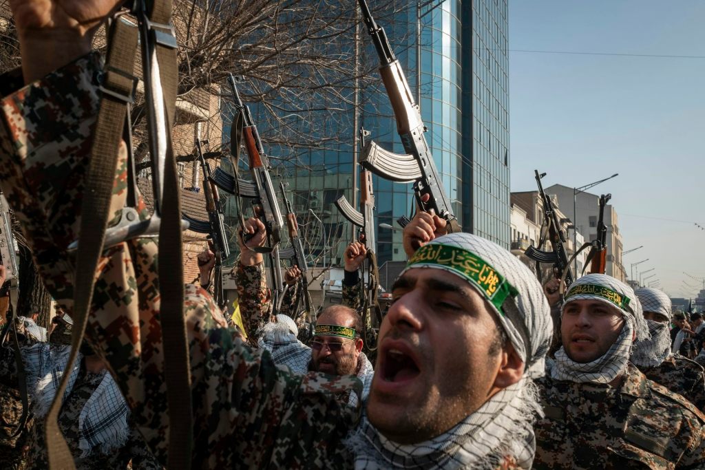 Several men wearing military garb and hoisting rifles in the air.