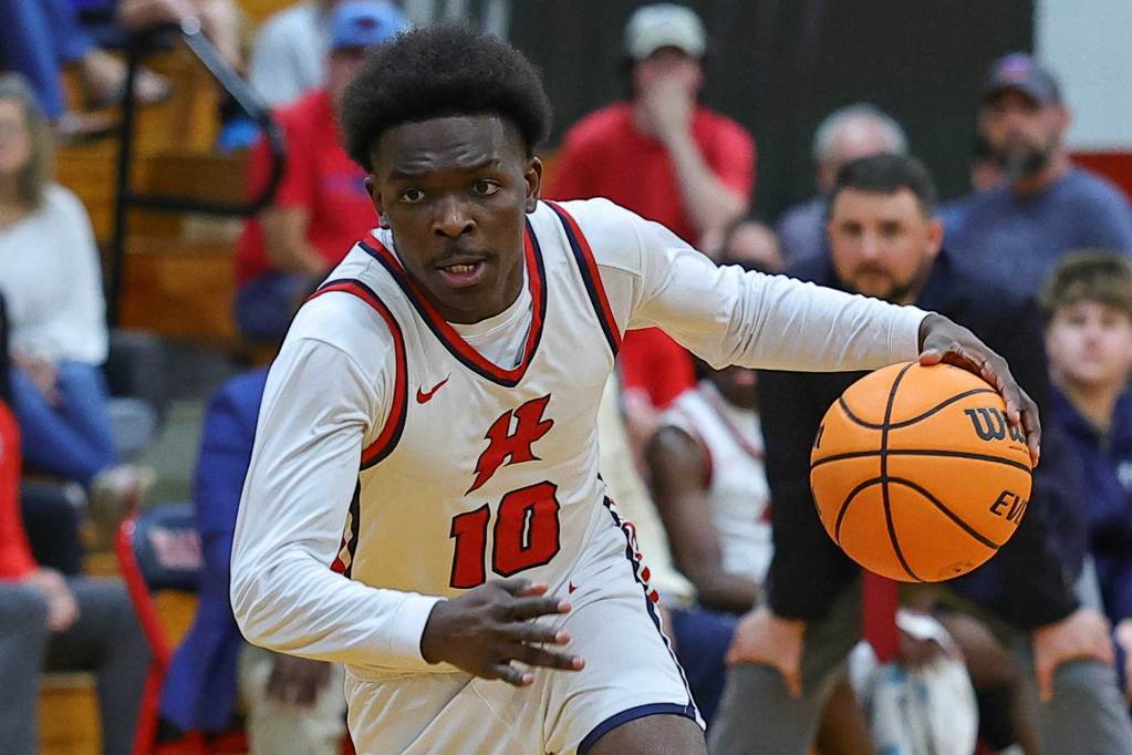 A young man with a number 10 jersey runs a basketball across the court