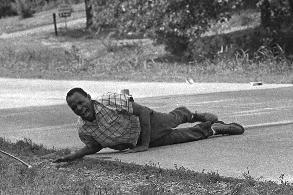 An older black and white photo of James Meredith crawling by the roadside, in pain
