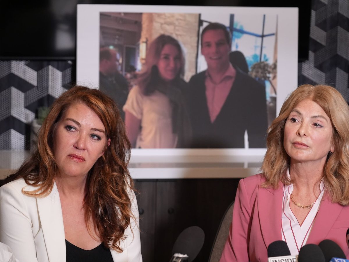 Lonna Drewes and her lawyer speak in front of a row of microphones at a press event