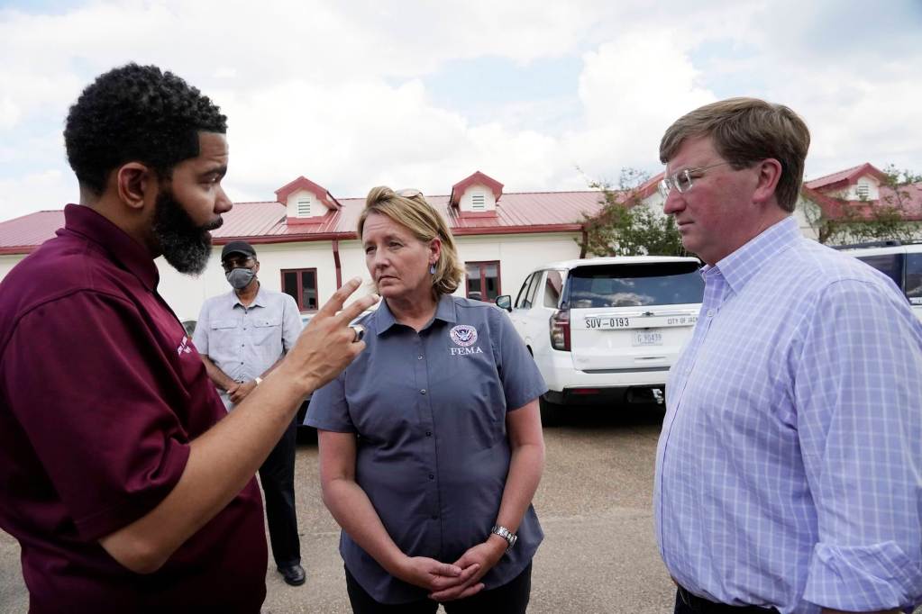 Chokwe A. Lumumba and Tate Reeves speak with FEMA official Deanne Criswell outside of a Jackson water plant