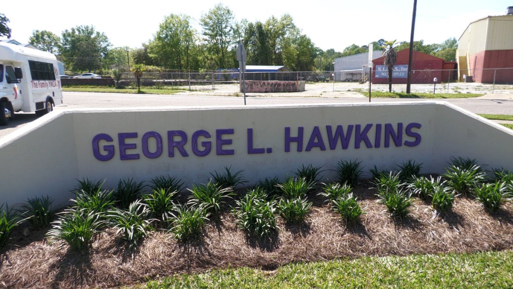 A sign for George L. Hawkins stands in front of a landscaped school entrance.