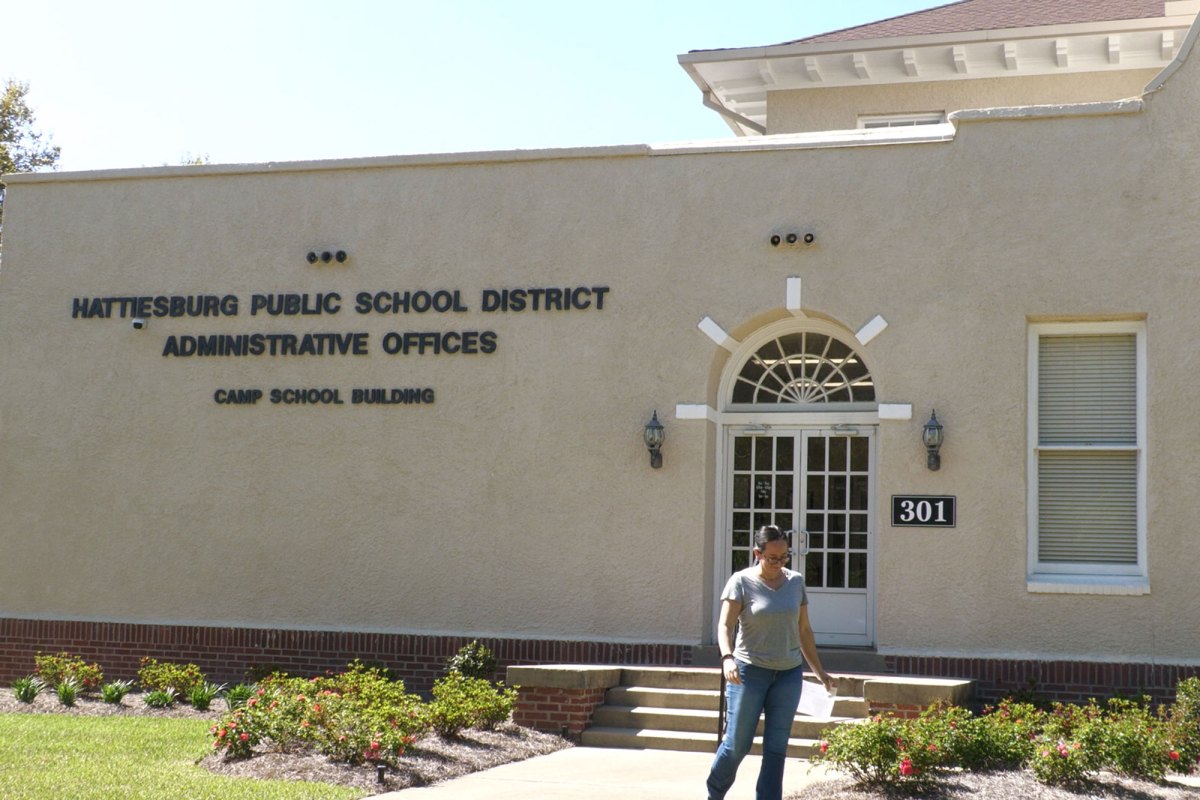 The exterior of the Hattiesburg Public School District administrative offices, with a person walking near the entrance.