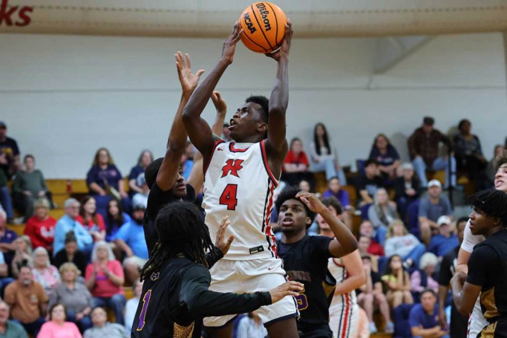 A young basketball player jumps over the other team to dunk a ball