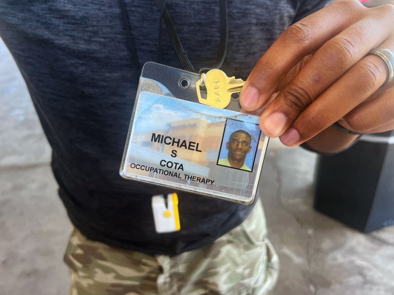 a black man holds a badge of his name and a picture of himself