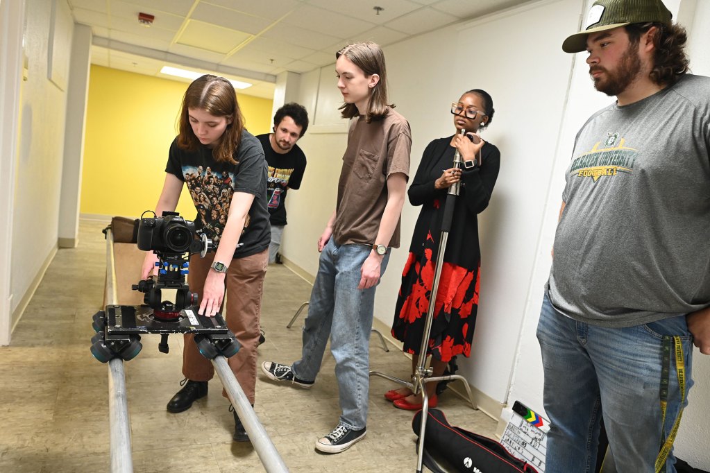 Students operating a camera on rails down a hallway