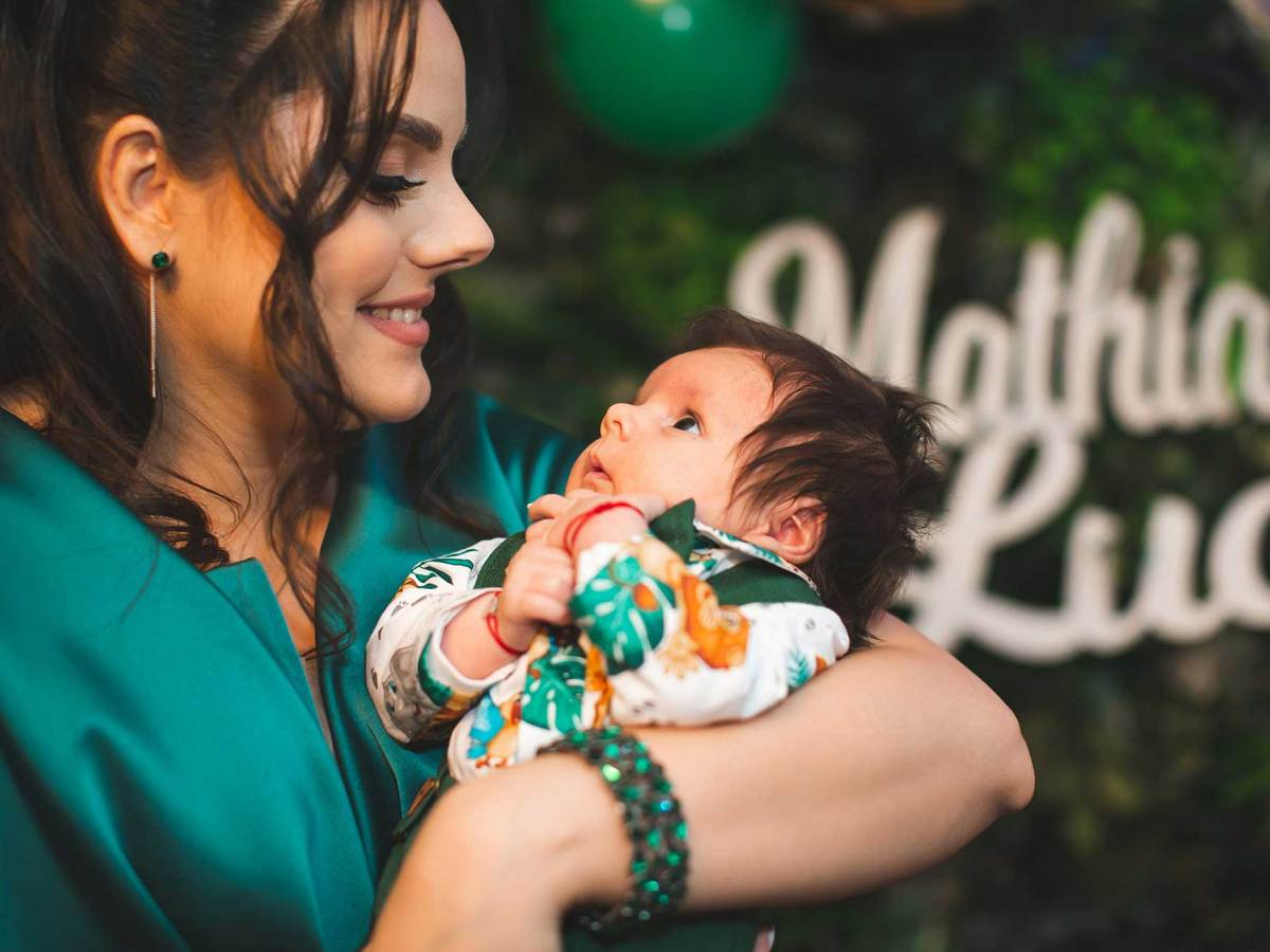 A woman in green holding an infant child at a party