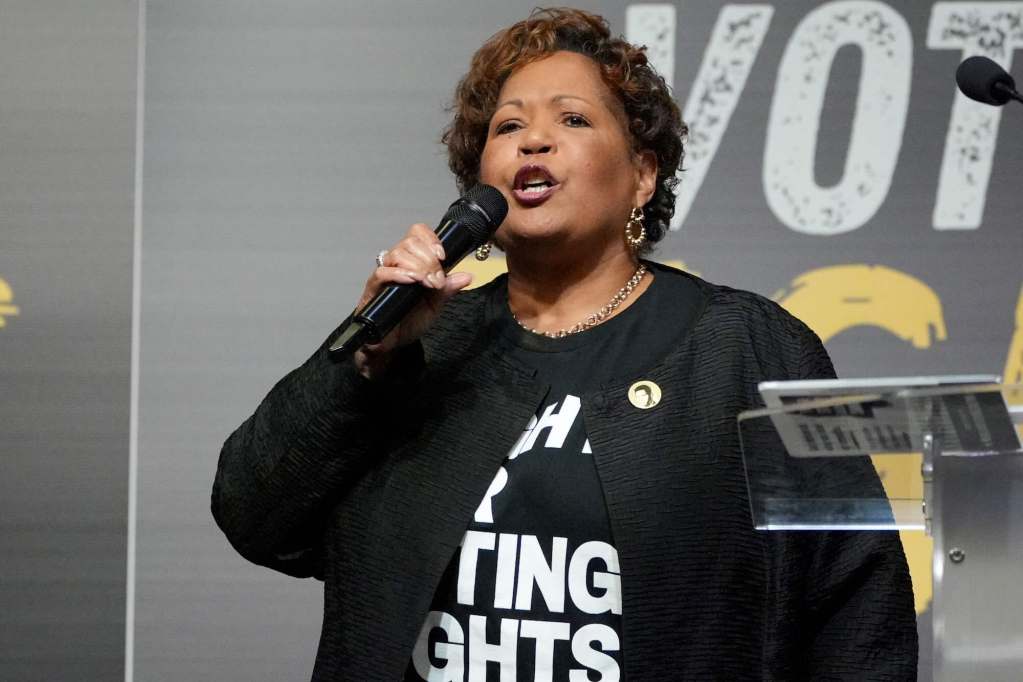 A closeup of Reena Evers-Everette speaking on stage. You can partially see a tshirt under her jacket that says something about voting rights