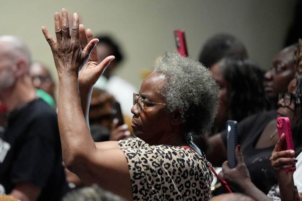 A closeup of a woman clapping in the audience of a meeting