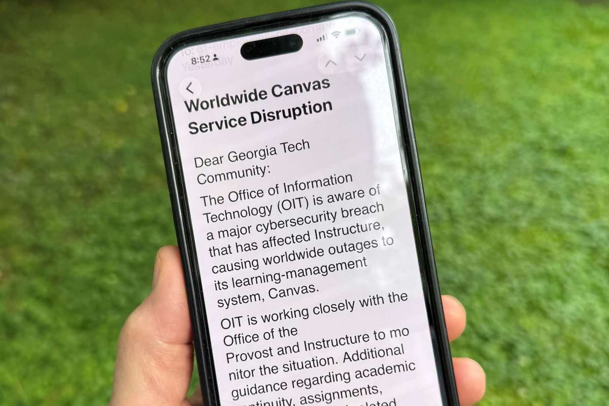 A hand holds a mobile phone outside that read 'Worldwide Canvas Service Disruption Dear Georgia Tech Community: The Office of Information Technology (OIT) is aware of a major cybersecurity breach that has affected Instructure, causing worldwide outages to its learning-management system, Canvas. OIT is working closely with the Office of the Provost and Instructure to monitor the situation. Additional guidance regarding academic...'