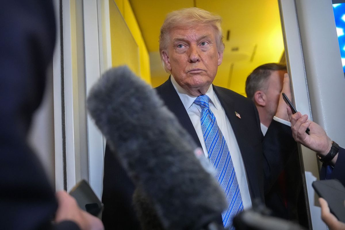 Donald Trump standing in a doorway with reporters around him