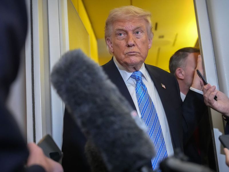 Donald Trump standing in a doorway with reporters around him