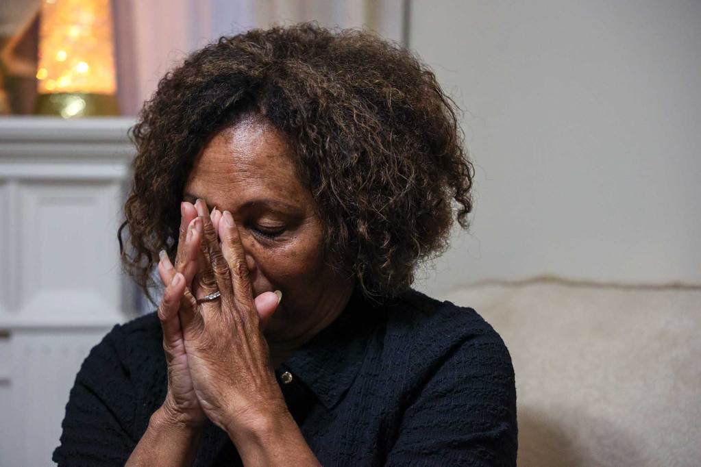Gail Baptiste, seated in her living room, resting her face against her clasped hands