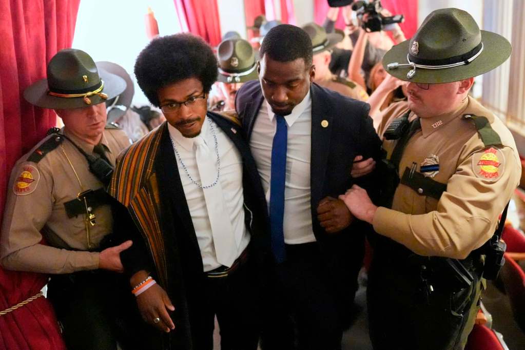 Two black men wearing suits being arrested by white officers inside the Tennessee capital