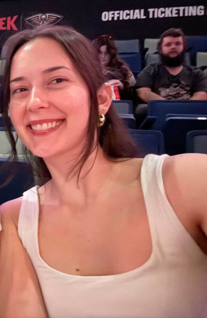 A selfie of a woman in a white top, seated at a music event