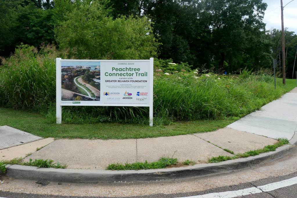 A sign reading ‘Peachtree connector trail’ is erected next to a sidewalk near Murrah High School