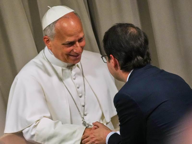 Pope Leo XIV shakes the hand of Christopher Olah, pictured from behind