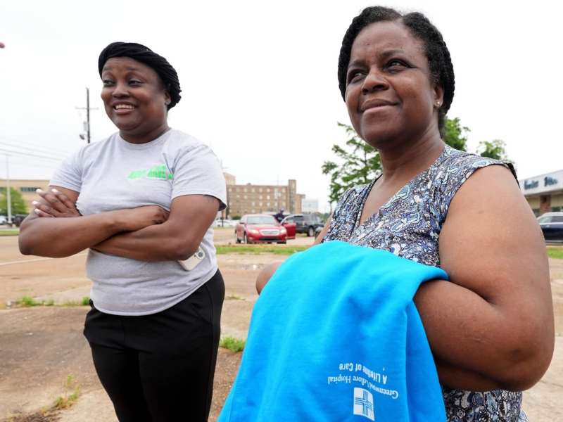 Two women stand in the parking lot outside of a hospital