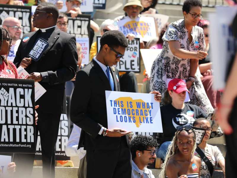 People gathered on the steps of the South Carolina Statehouse holding signs, such as "This Is What Democracy Looks Like" and "Black Voters Matter"