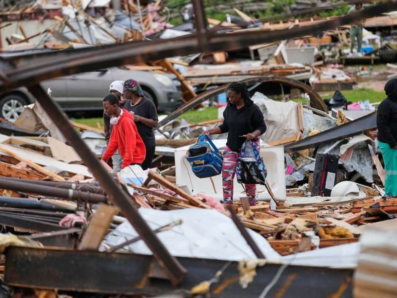 Several women gather materials from the wreckage of destroyed homes