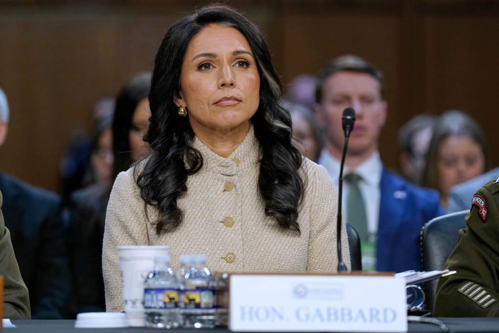 Tulsi Gabbard seated at a table with people seated in the background behind her